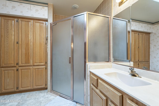 full bathroom featuring a stall shower, vanity, and wallpapered walls