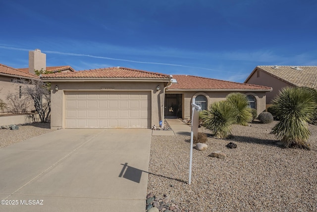 view of front facade with a garage, driveway, a tiled roof, and stucco siding