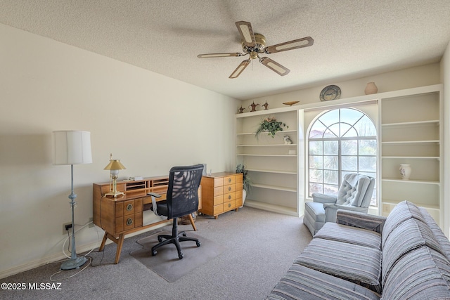 office area featuring a ceiling fan, a textured ceiling, and light colored carpet