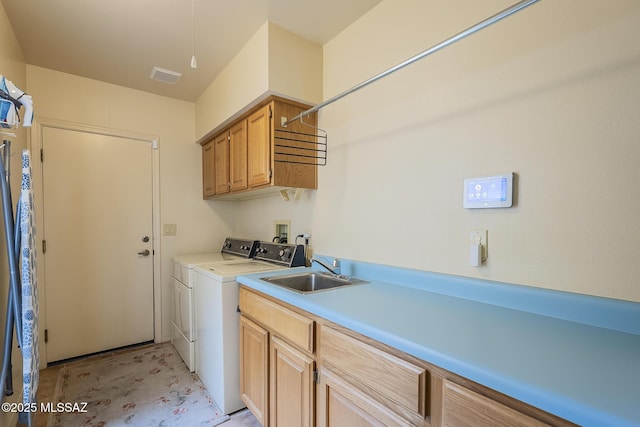 laundry room with washing machine and dryer, cabinet space, a sink, and visible vents