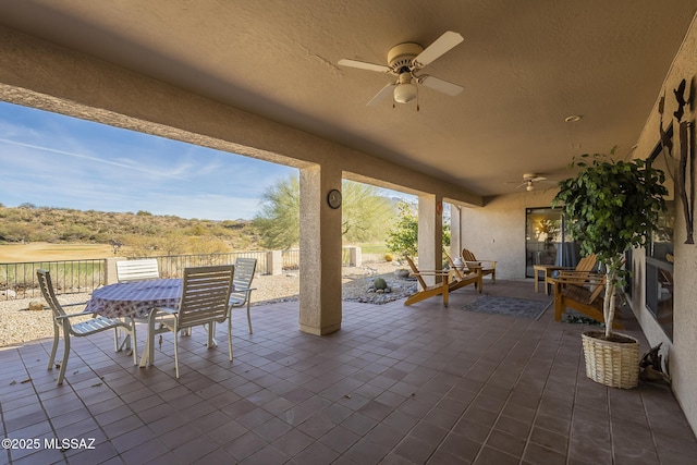 view of patio with ceiling fan, fence, and outdoor dining area