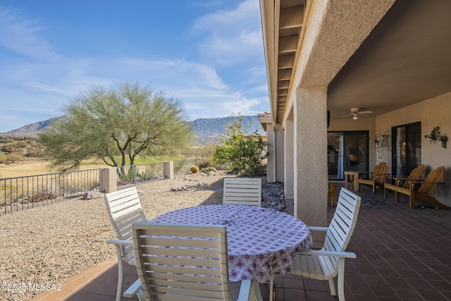 view of patio / terrace with outdoor dining space, fence private yard, a mountain view, and a ceiling fan