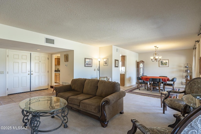 living area with light tile patterned floors, visible vents, a chandelier, and a textured ceiling