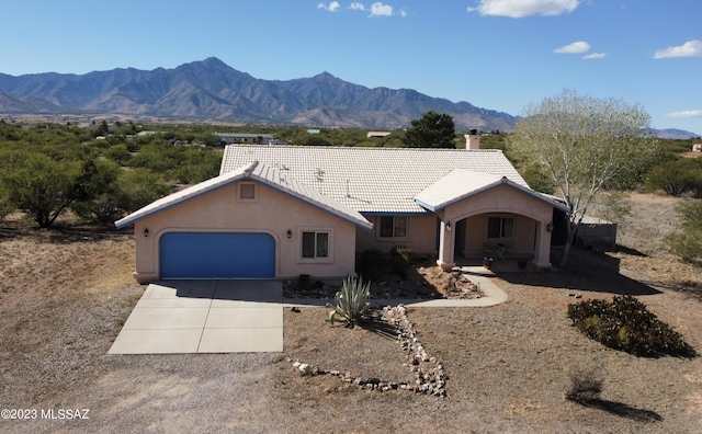 ranch-style house featuring a mountain view, a garage, concrete driveway, a tiled roof, and stucco siding