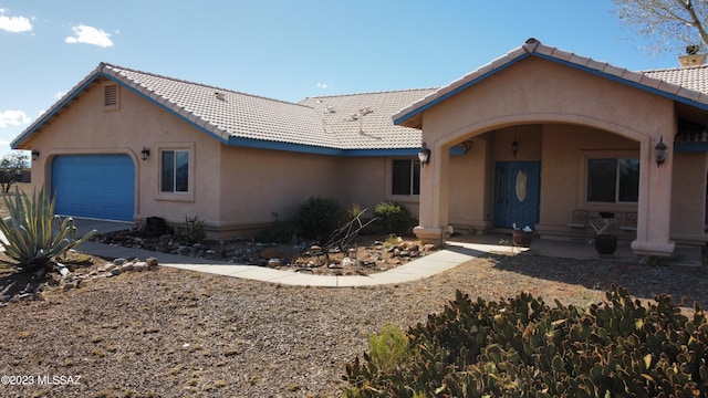 view of front of house featuring an attached garage, a tiled roof, and stucco siding