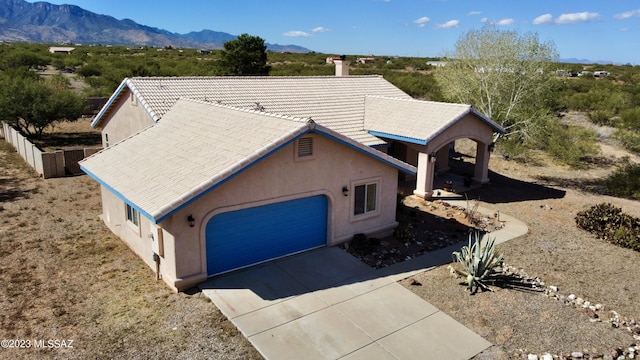 view of front of house featuring a garage, driveway, a tile roof, a mountain view, and stucco siding