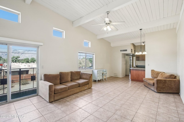 living area featuring light tile patterned floors, visible vents, beam ceiling, and ceiling fan with notable chandelier