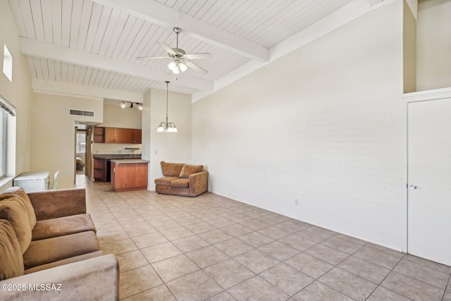 living area featuring light tile patterned floors, visible vents, beam ceiling, and ceiling fan with notable chandelier