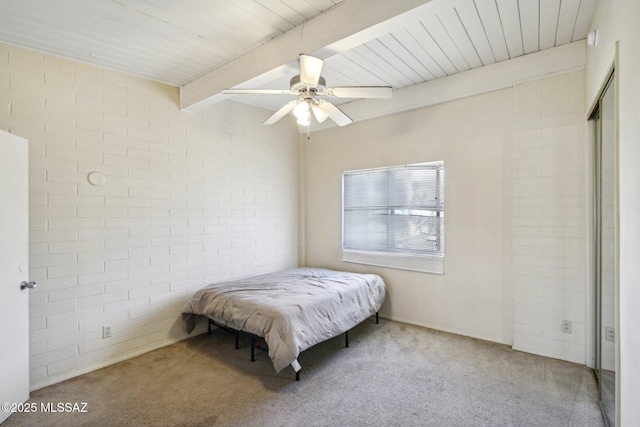 bedroom with a ceiling fan, wood ceiling, carpet flooring, brick wall, and beamed ceiling