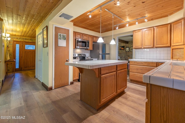 kitchen featuring light wood-style flooring, appliances with stainless steel finishes, tile counters, and wooden ceiling