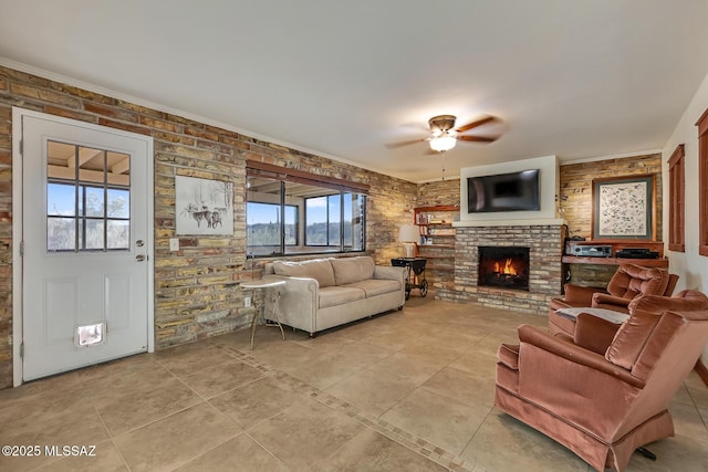 living area featuring light tile patterned floors, a fireplace, brick wall, and ceiling fan