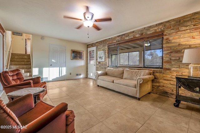 living area featuring visible vents, brick wall, stairs, light tile patterned flooring, and a ceiling fan