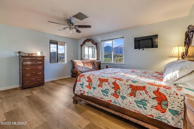 bedroom with ceiling fan, wood finished floors, visible vents, and baseboards