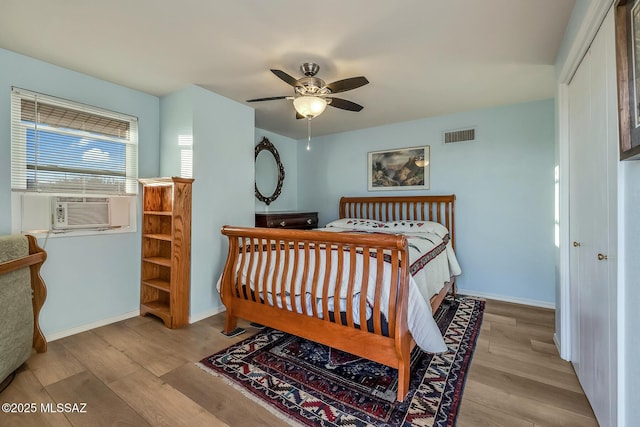 bedroom with cooling unit, wood finished floors, visible vents, baseboards, and a closet