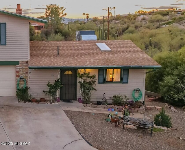 view of front of house with concrete driveway and roof with shingles