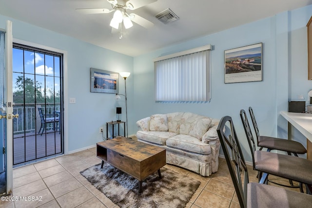 living room featuring light tile patterned floors, visible vents, baseboards, and ceiling fan