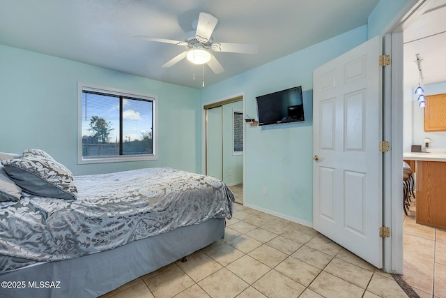 bedroom featuring light tile patterned floors, baseboards, a closet, and ceiling fan