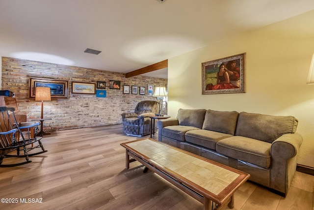 living area with visible vents, beamed ceiling, and wood finished floors