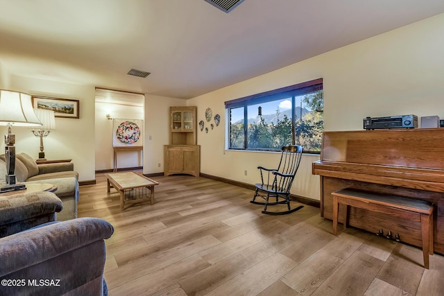 living room with visible vents, baseboards, and wood finished floors