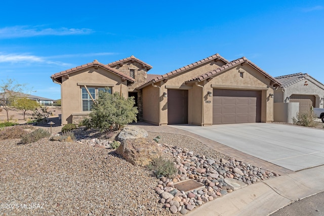 mediterranean / spanish-style house featuring a garage, stone siding, driveway, and stucco siding