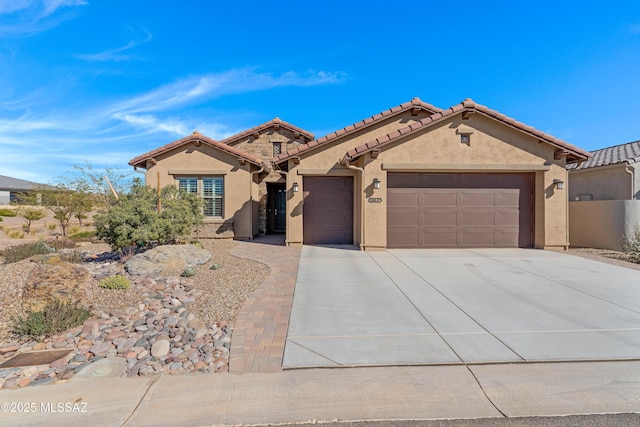 mediterranean / spanish house with a garage, concrete driveway, a tiled roof, and stucco siding