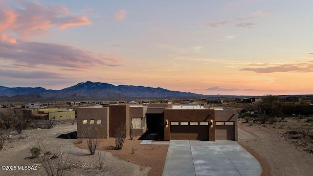 view of front of house with a mountain view, driveway, an attached garage, and stucco siding