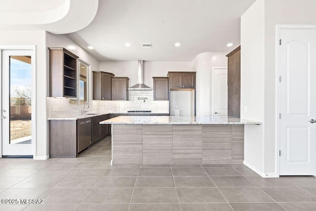 kitchen featuring light stone counters, stainless steel dishwasher, light tile patterned flooring, a sink, and wall chimney exhaust hood