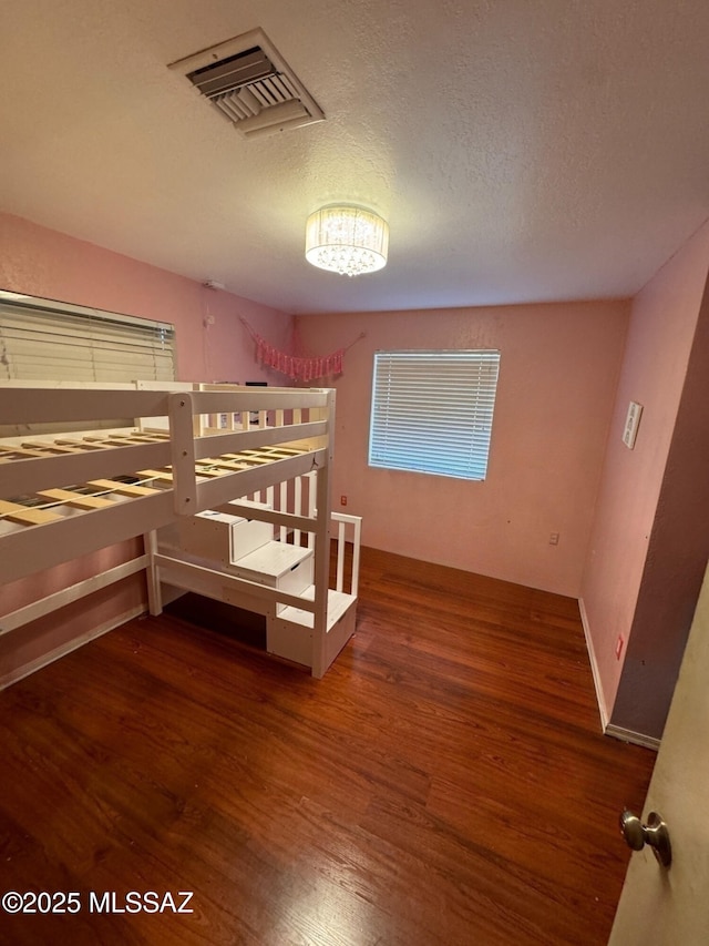 bedroom featuring visible vents, dark wood finished floors, and a textured ceiling