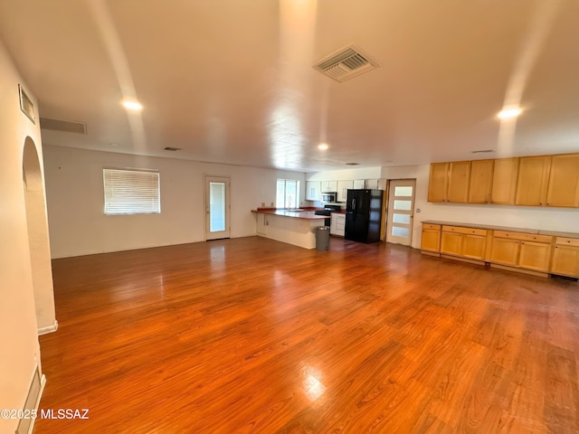 kitchen with visible vents, dark countertops, open floor plan, freestanding refrigerator, and light wood-style floors