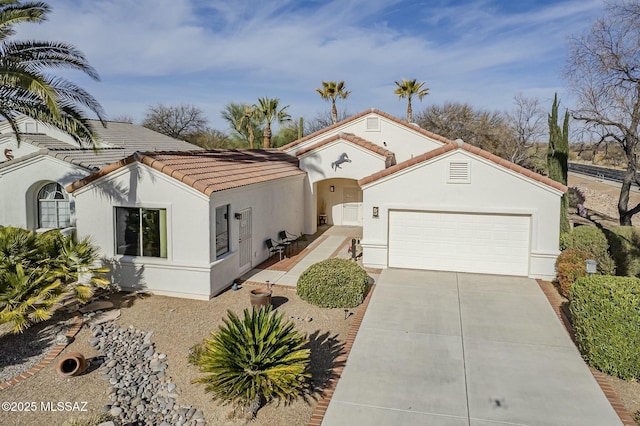 mediterranean / spanish-style home featuring a garage, concrete driveway, a tile roof, and stucco siding