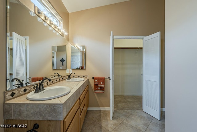 bathroom featuring tile patterned flooring, a sink, baseboards, and double vanity