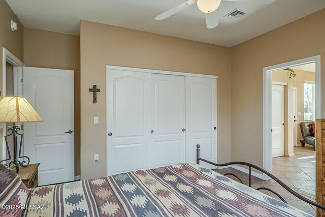 bedroom with tile patterned flooring, visible vents, baseboards, a ceiling fan, and a closet