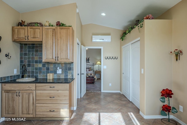 kitchen featuring lofted ceiling, decorative backsplash, a sink, a wall mounted air conditioner, and baseboards