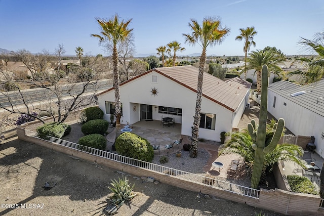 exterior space with a patio area, a fenced backyard, a tiled roof, and stucco siding