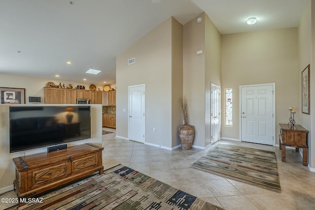 entrance foyer with light tile patterned floors, recessed lighting, visible vents, a high ceiling, and baseboards