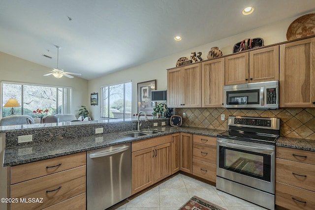 kitchen with light tile patterned floors, backsplash, vaulted ceiling, stainless steel appliances, and a sink