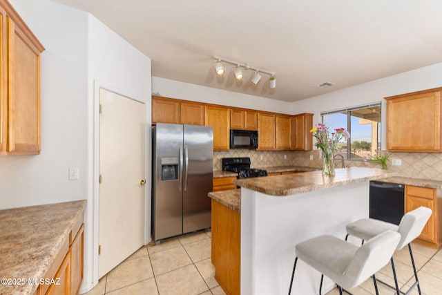 kitchen with a center island, light tile patterned floors, decorative backsplash, black appliances, and a kitchen bar