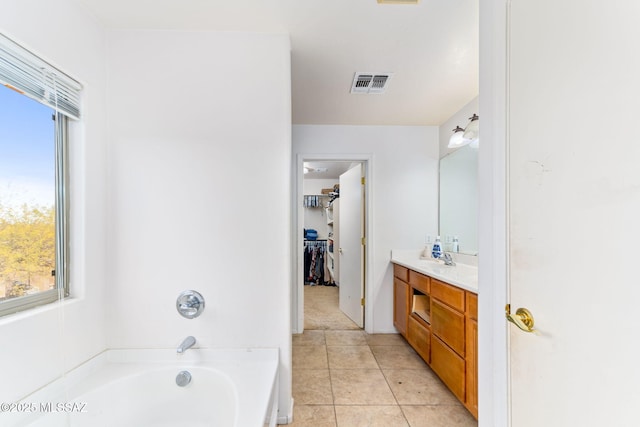 full bathroom featuring visible vents, tile patterned floors, a spacious closet, vanity, and a bath