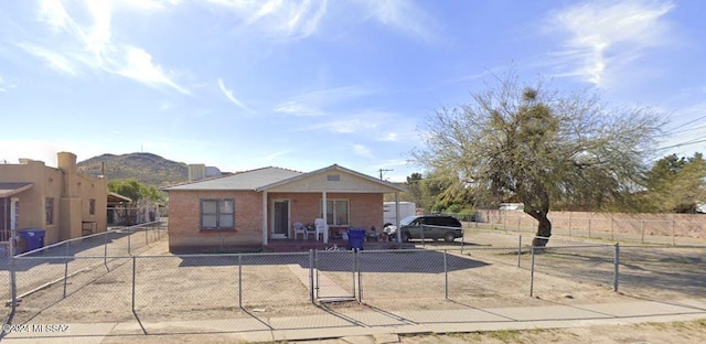 view of front of house featuring a fenced front yard, a gate, a mountain view, and brick siding