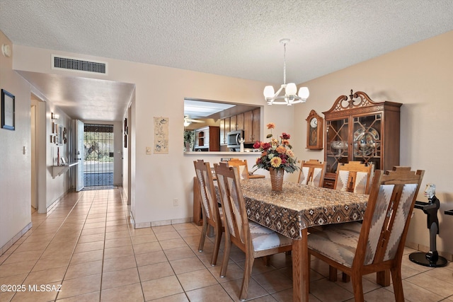 tiled dining area with ceiling fan with notable chandelier and a textured ceiling