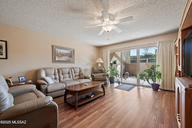 living room featuring hardwood / wood-style flooring, ceiling fan, and a textured ceiling