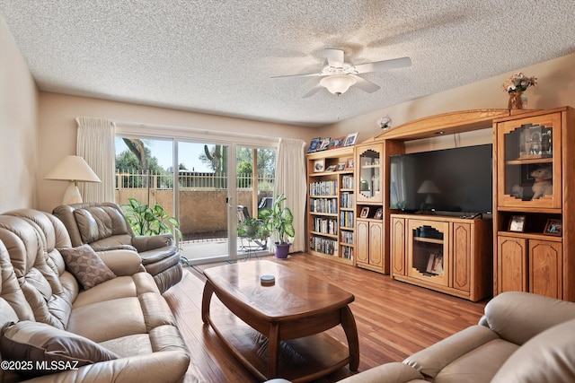 living room with ceiling fan, wood-type flooring, and a textured ceiling