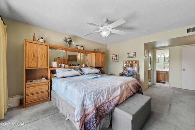 carpeted bedroom featuring a textured ceiling and ensuite bathroom