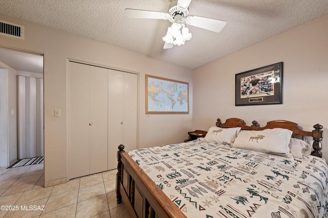 tiled bedroom with a closet, ceiling fan, and a textured ceiling