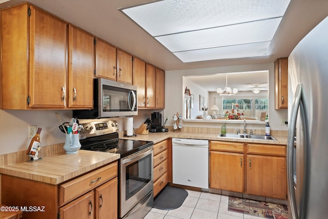 kitchen featuring appliances with stainless steel finishes, sink, a chandelier, light tile patterned floors, and decorative light fixtures