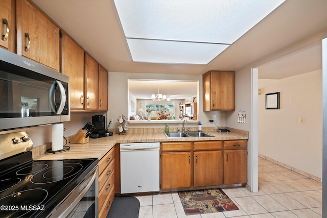 kitchen with appliances with stainless steel finishes, sink, light tile patterned floors, and a notable chandelier