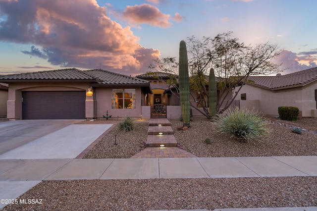 view of front of house with a garage, driveway, a tiled roof, and stucco siding