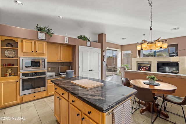 kitchen with a fireplace, stainless steel appliances, visible vents, decorative backsplash, and a kitchen island