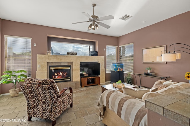 living room with baseboards, a fireplace, visible vents, and a ceiling fan