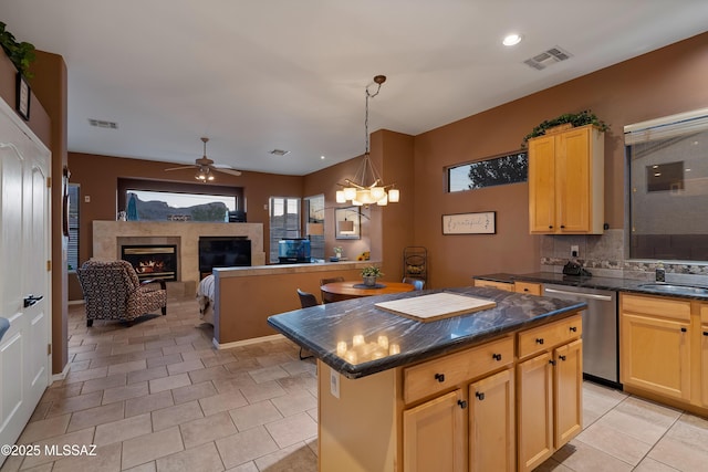 kitchen with stainless steel dishwasher, a fireplace, visible vents, and a center island